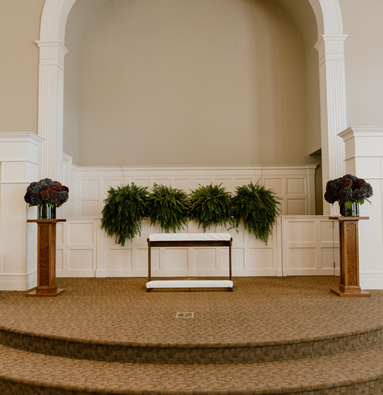 Handmade white kneeling bench in the center of the altar for a wedding.