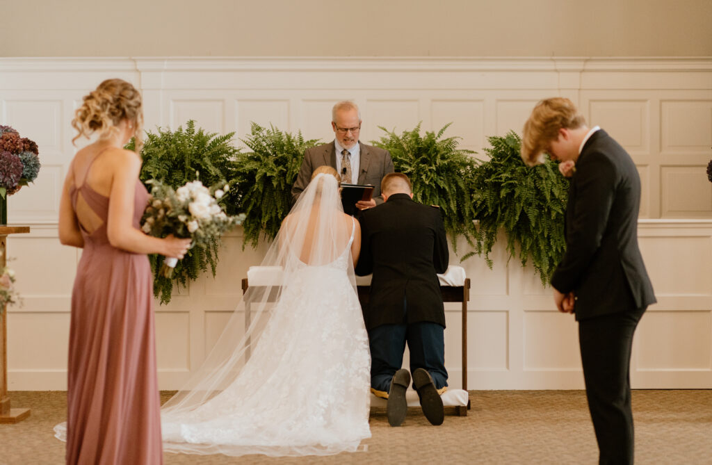 Bride and groom praying at the handmade kneeling bench during their wedding ceremony.